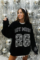 Woman in black sweatshirt with lace bow detailing in front of a new years background