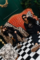 Two women sitting on a red couch with leopard print accents in a stylish room.