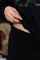 Close-up of a hand holding a black sweatshirt to show top of pant 