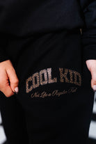 Black sweatshirt with 'Cool Kid Not Like a Regular Kid' text in leopard