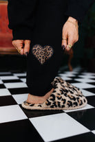 Person wearing leopard print slippers on a checkered floor