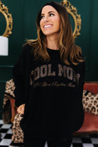 Woman wearing a black sweatshirt with text in a decorative room.