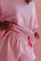 Person wearing a pink outfit with a Staykation label against a pink background