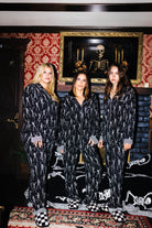 Three models wearing matching adult Skelly pajamas