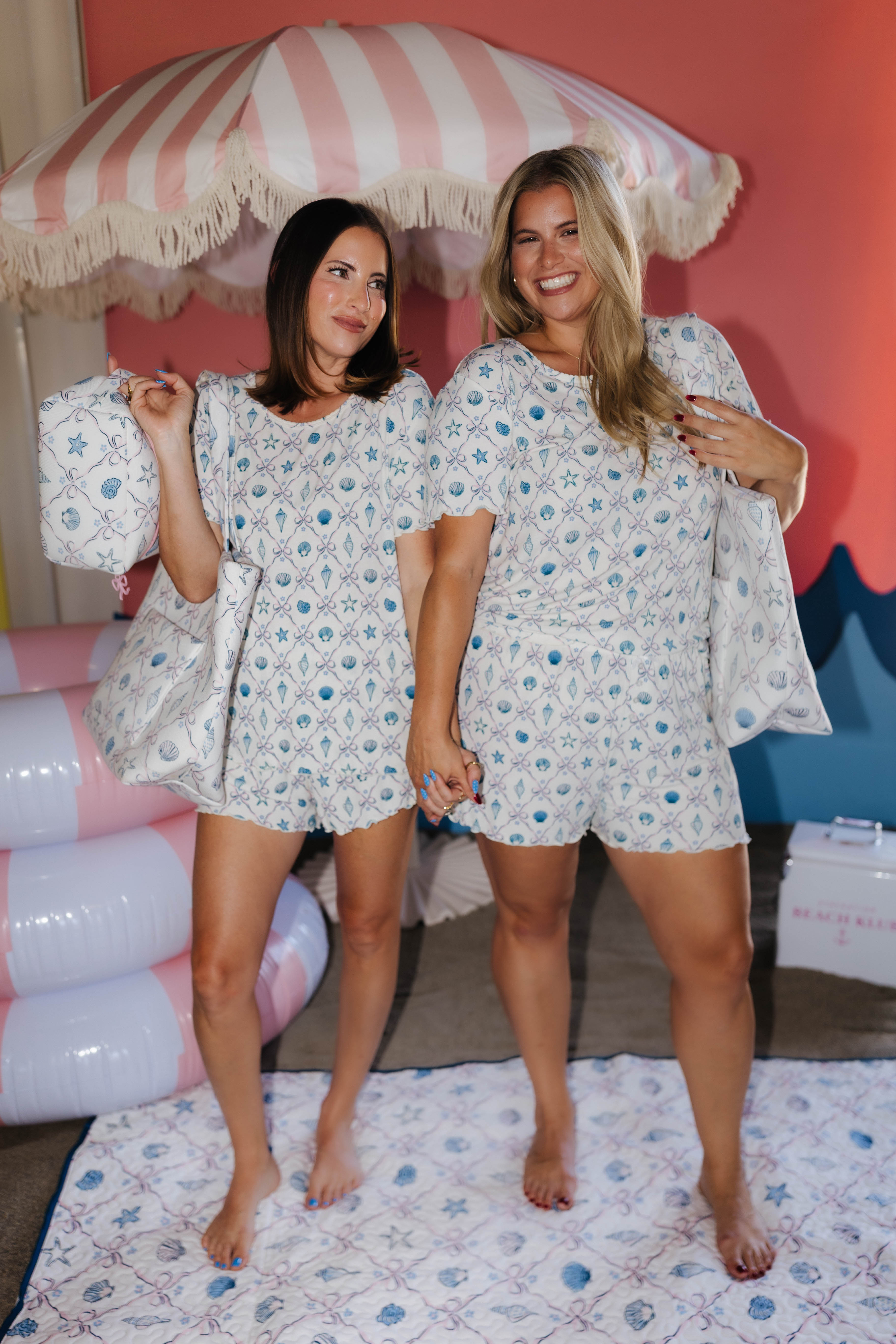 Two women wearing matching beach pjs standing in a room with colorful decor.