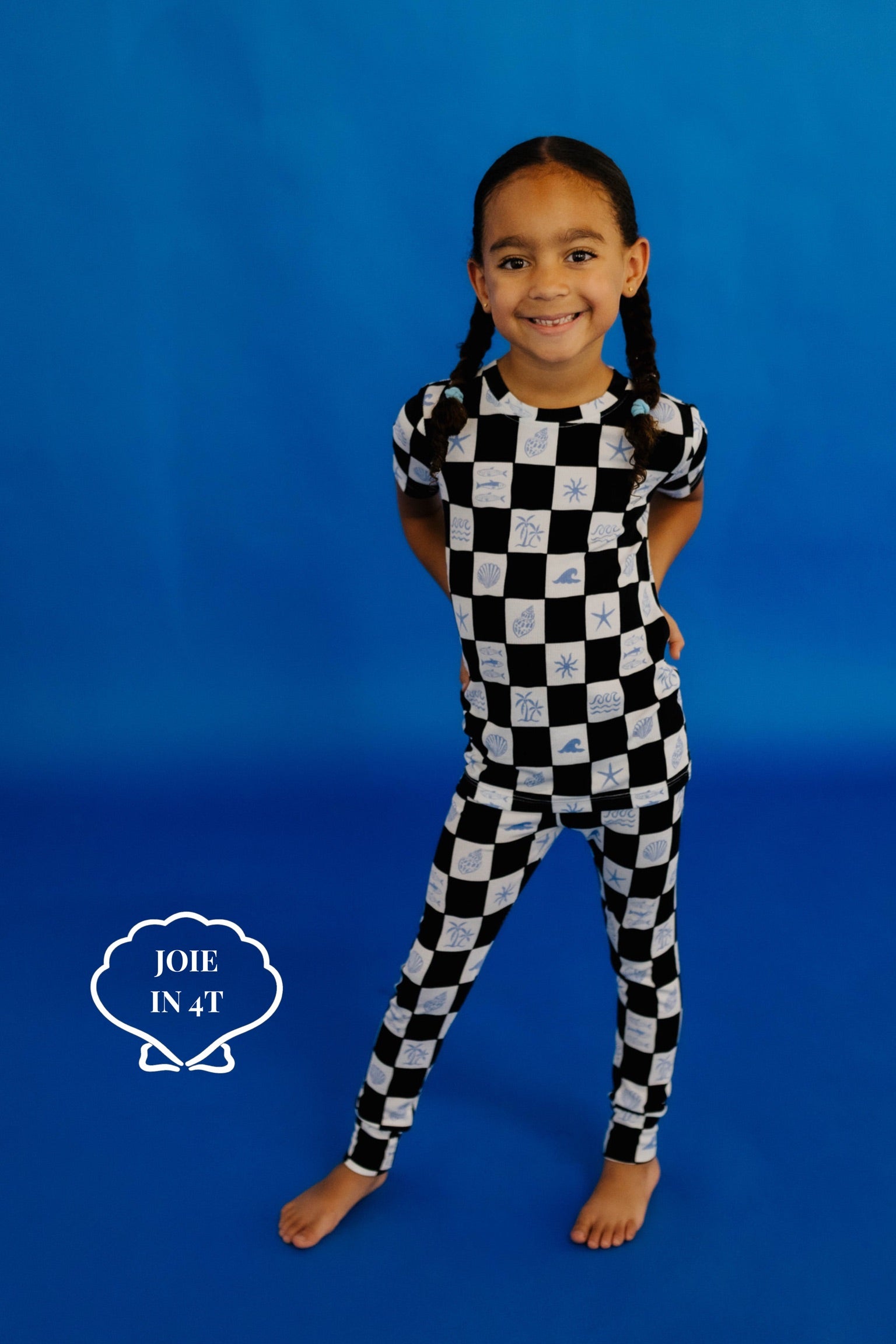 Child wearing a black and white checkered pj set on a blue background size 4t