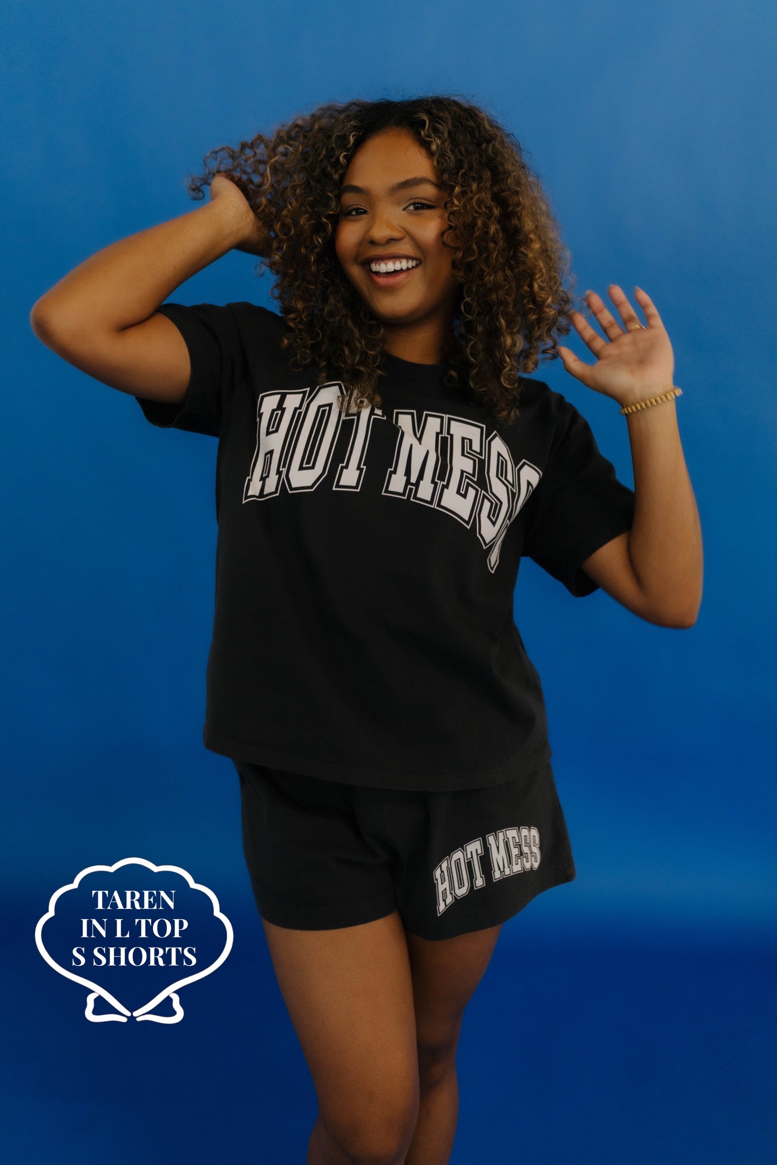 Person wearing a black 'HOT MESS' t-shirt and shorts against a blue background