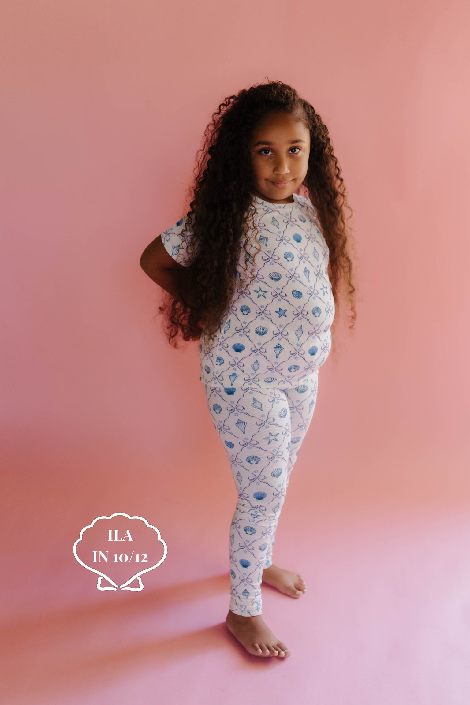 Young girl wearing a shell patterent outfit on a pink background