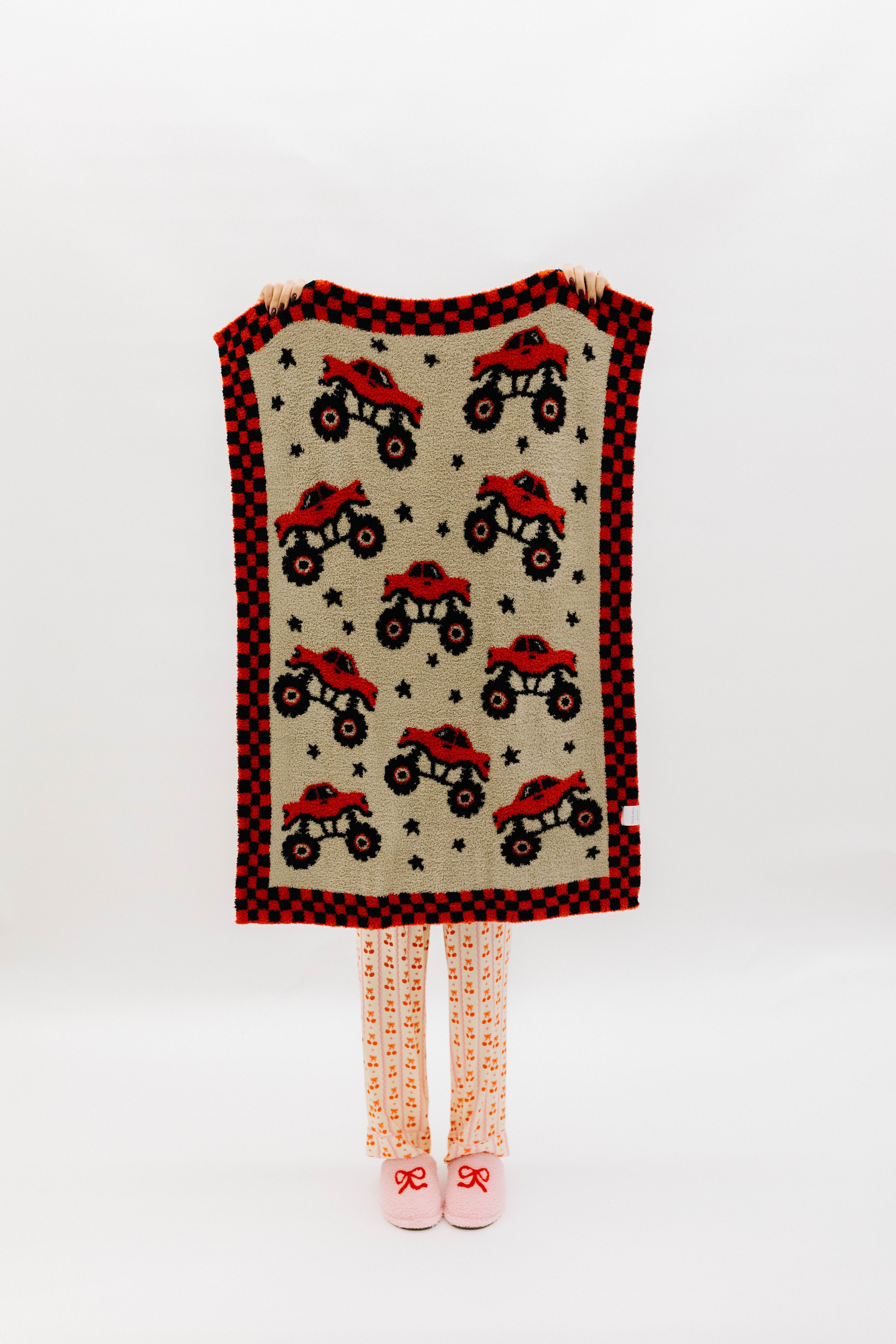 front of monster truck blanket showing the red and black monster trucks and black stars