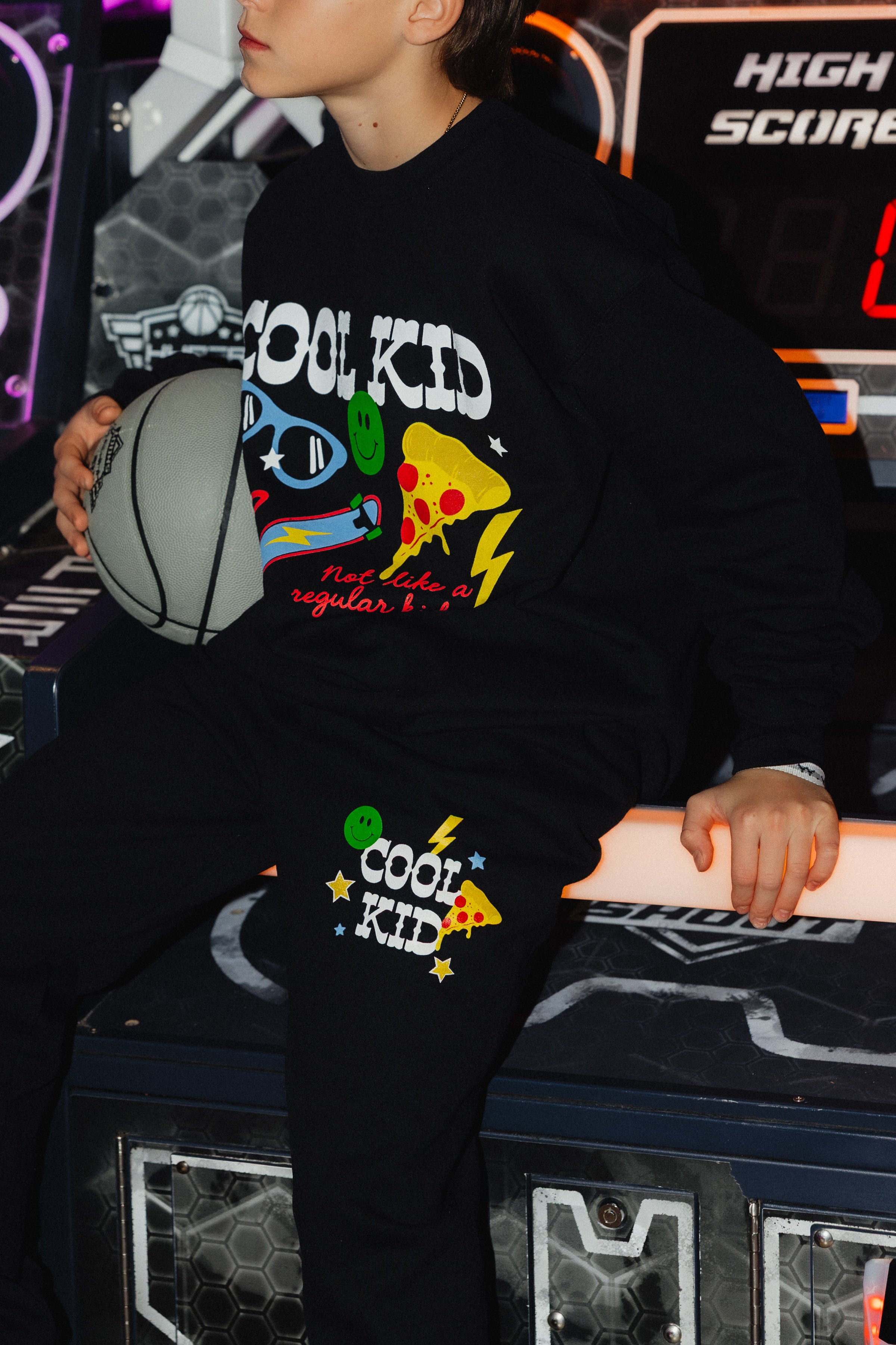 Boston holding a basketball showing the cool kid sweatpants with pizza and smiley lightning bolt and star