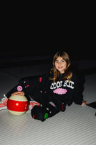 Kolly sitting on the ground of the bowling alley with the bowling ball. 