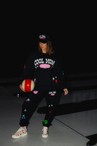krista holding a bowling ball wearing the cool mom sweatshirt with the matching hat and swetapnts