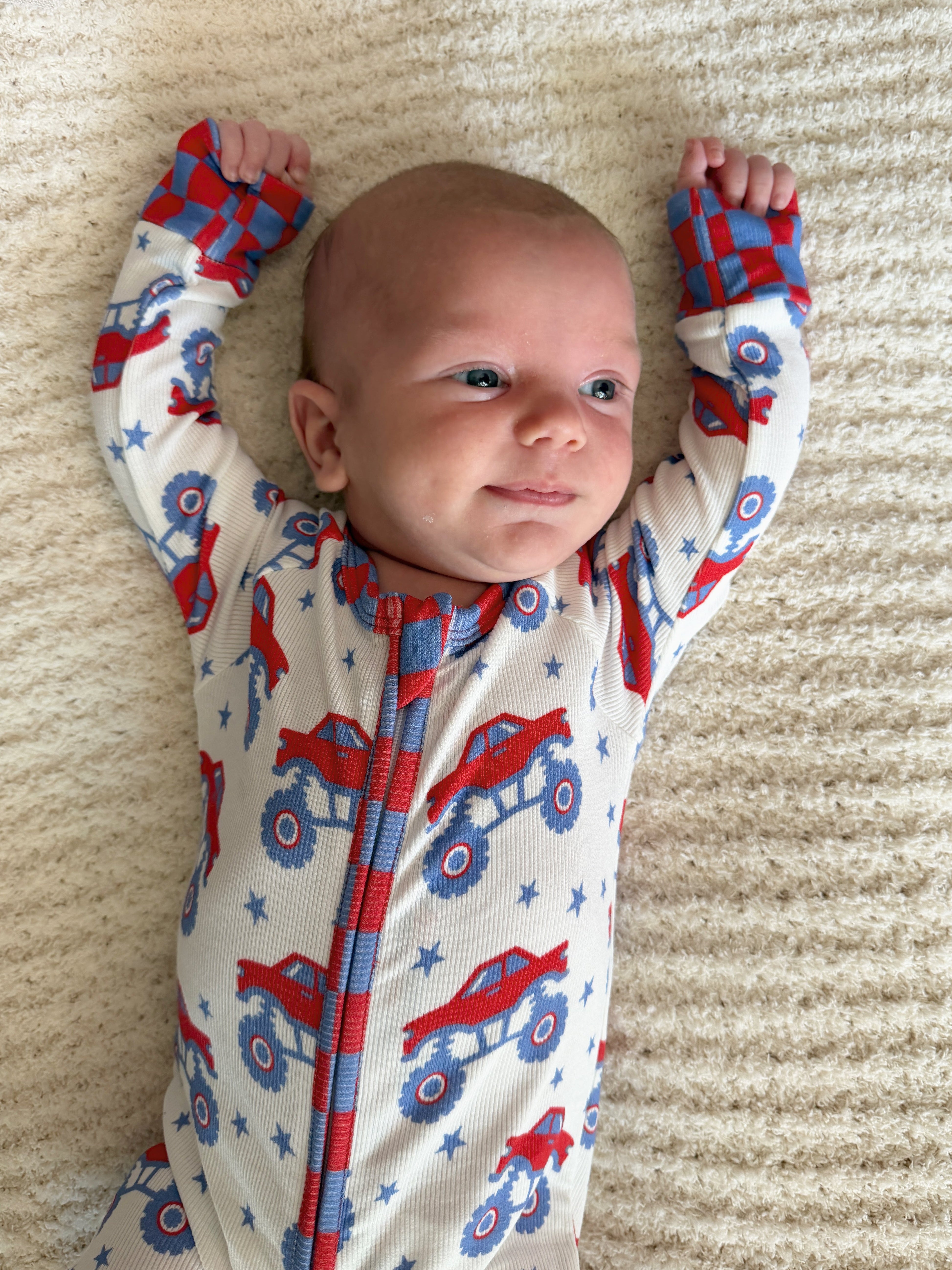 baby with arms up in monster pjs 