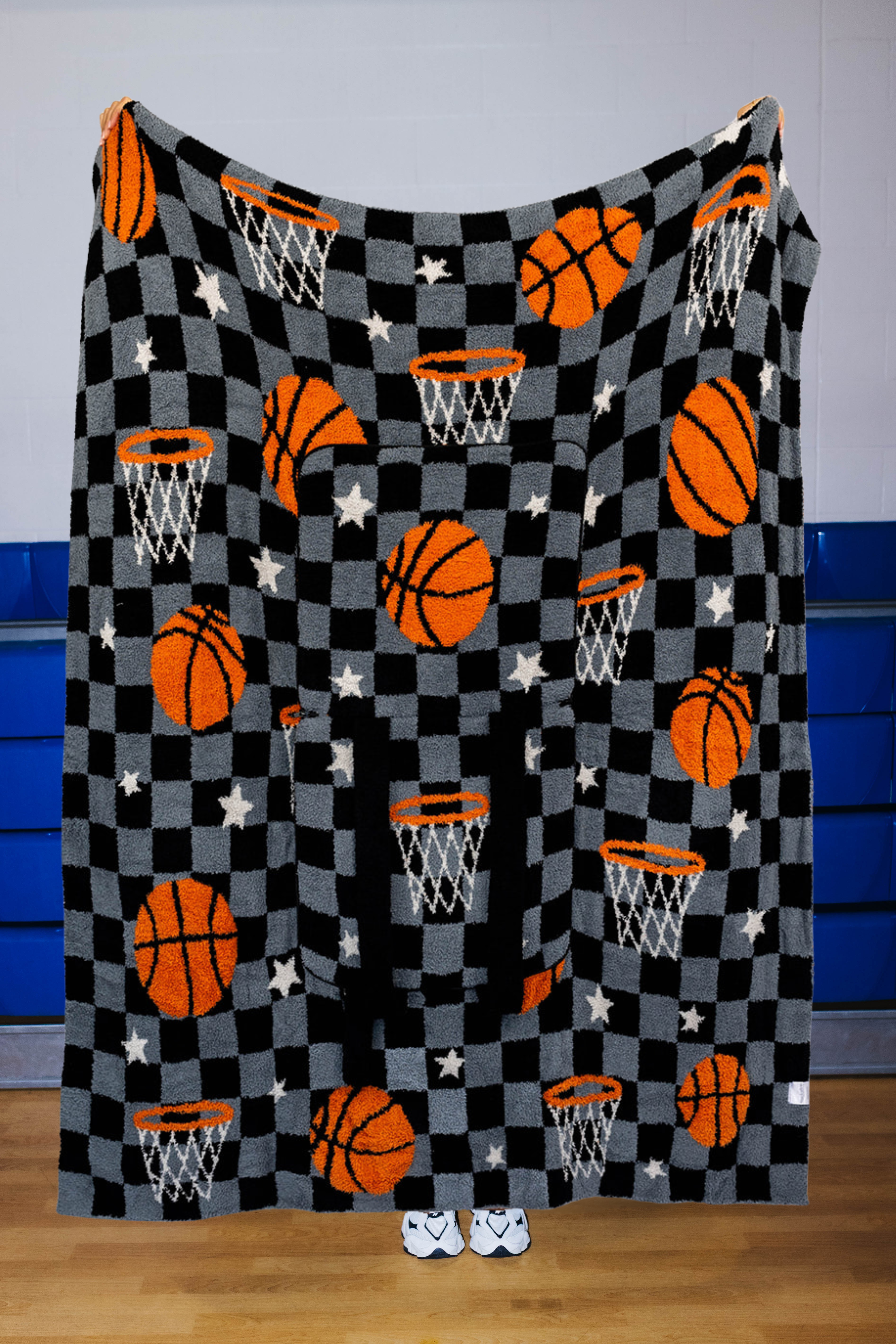 A black and gray checkered blanket featuring orange basketballs, white stars, and basketball hoops